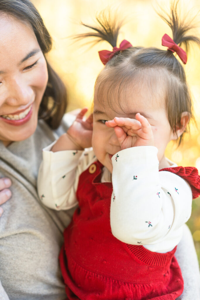 A small girl rubs her eye while her mom smiles at her. 
