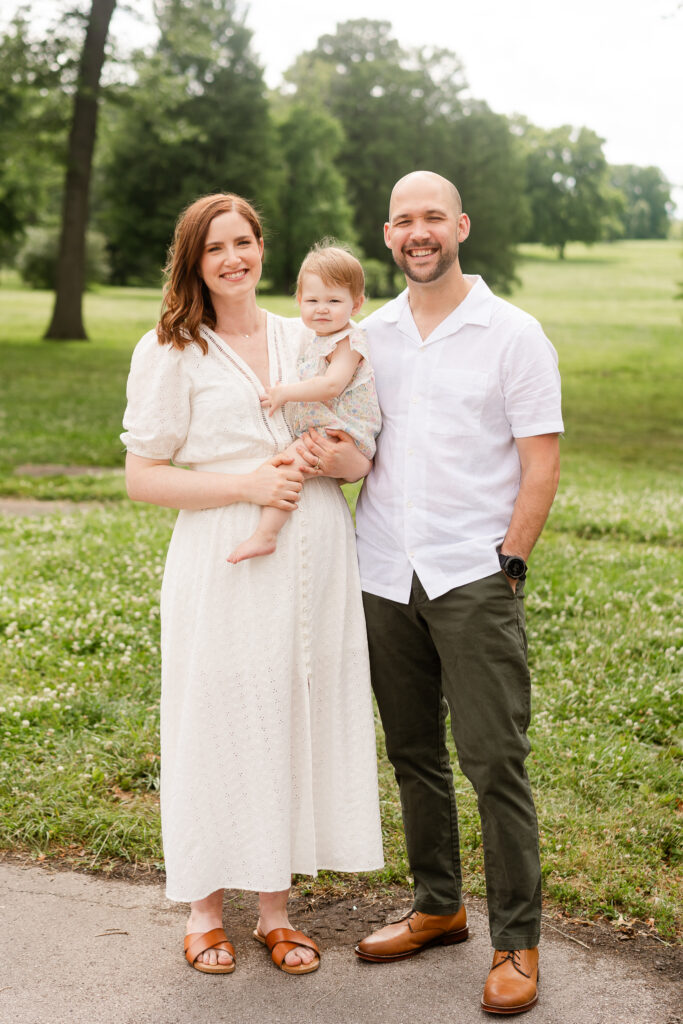 A family all smiling at the camera wearing bright outfits with a green background.