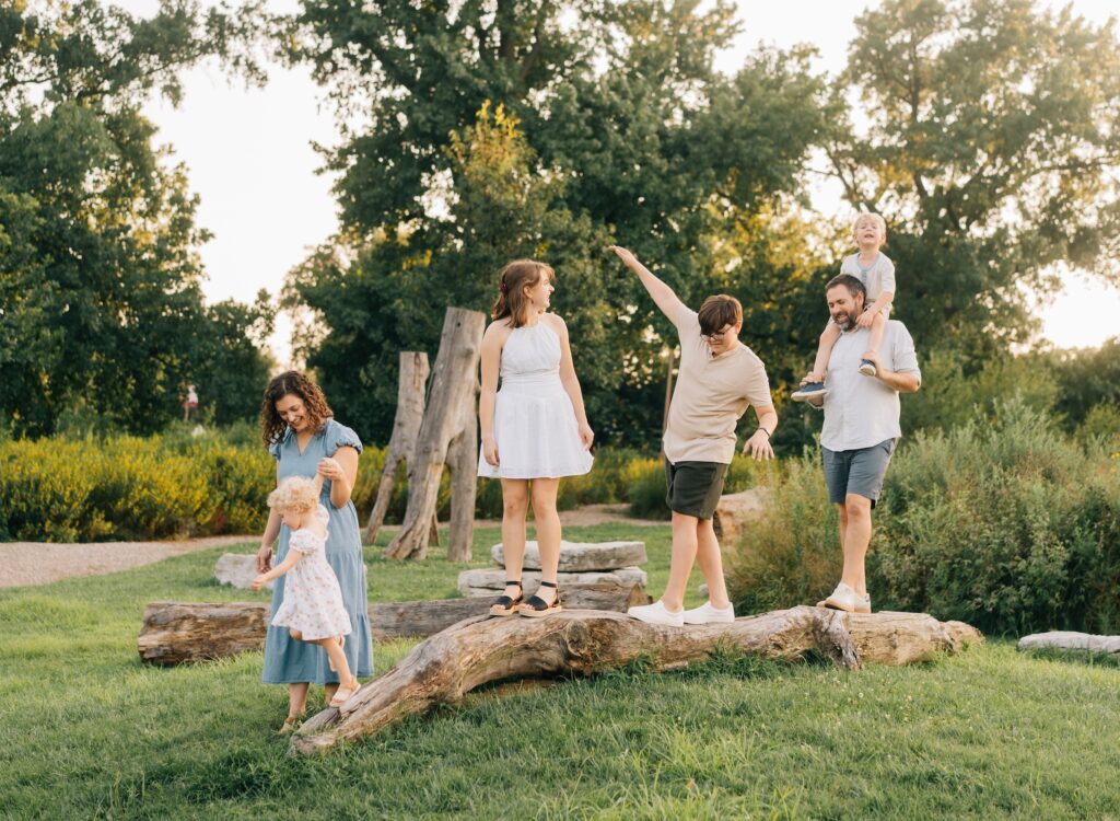 A family walking across a log for their Forest Park Nature Playscape family photos.