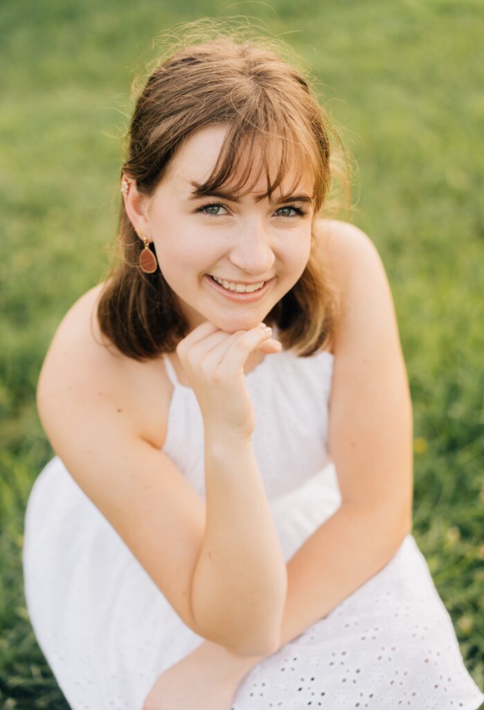 A teen girl smiling up at the camera, the photo is close up on her face.