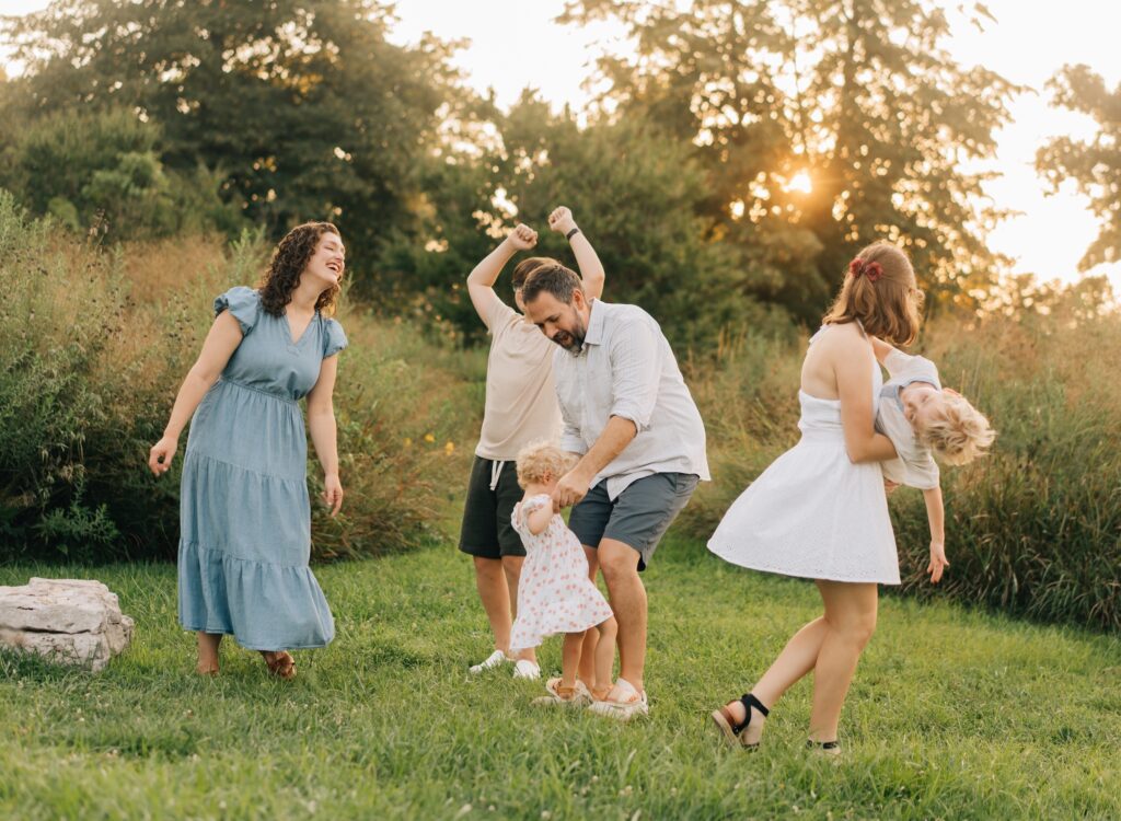A family dancing with the sun setting behind them in the Forest Park Nature Playscape.
