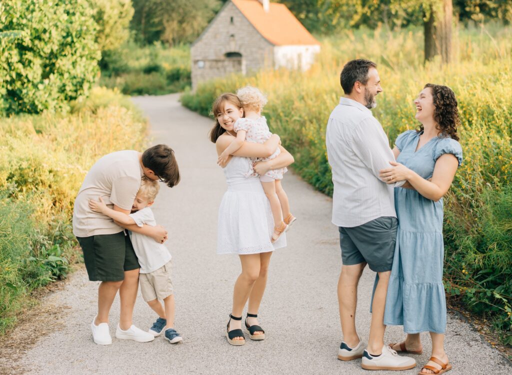 A family laughing and hugging each other at the forest park nature playscape.
