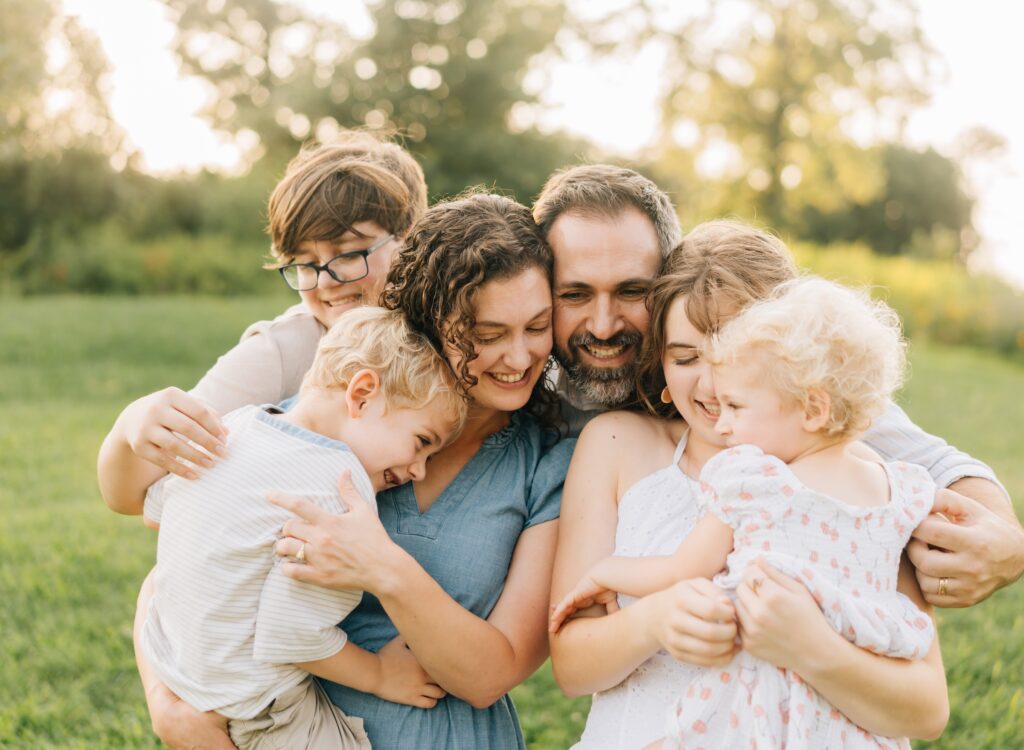 A family standing close together and smiling at each other for Forest Park Nature Playscape family photos.