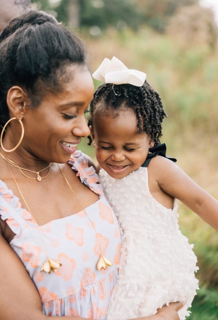 A mom holding her daughter. The daughter is making a silly face.