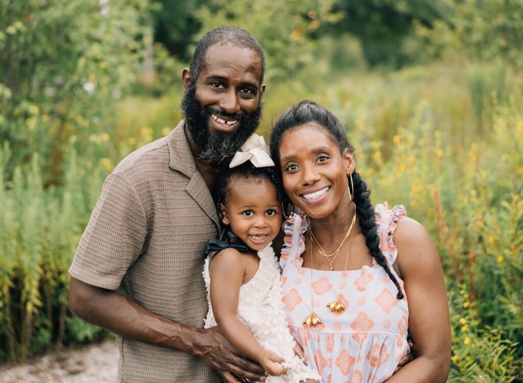 A family of three smiling at the camera.