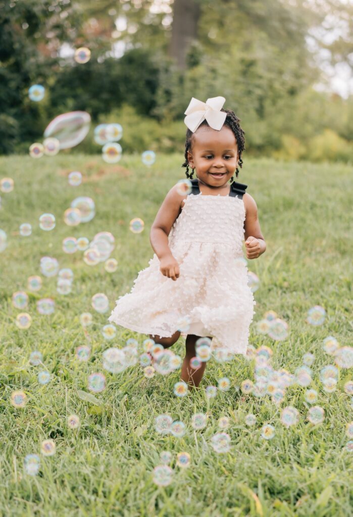 A toddler runs through bubbles. St. Louis outdoor family photos.