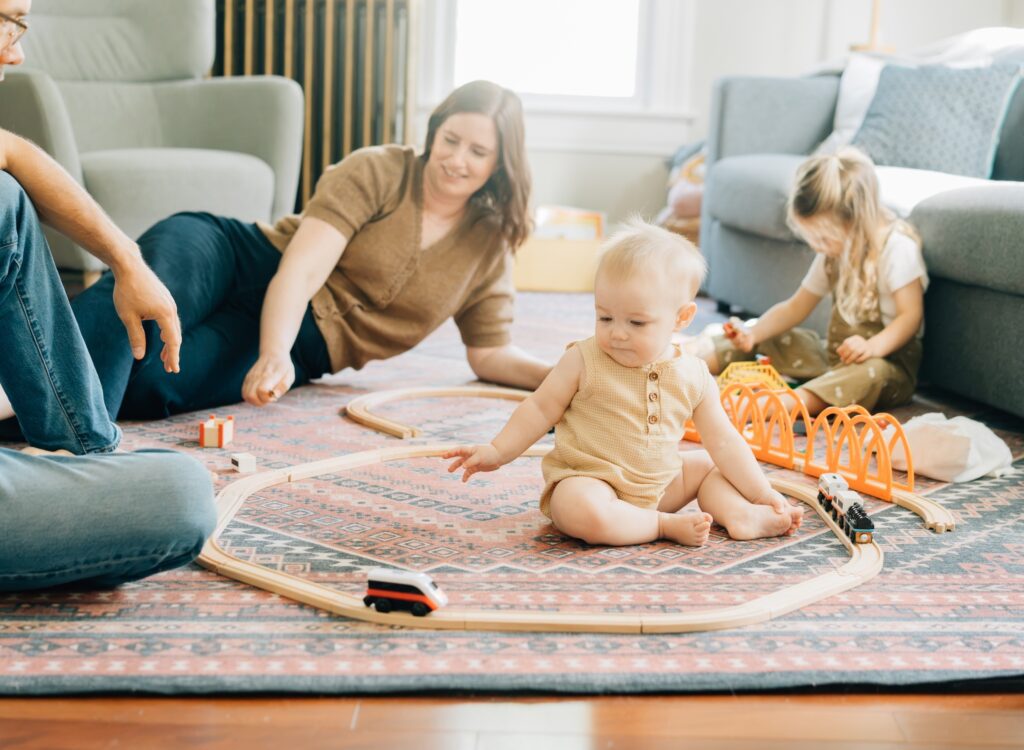 A family playing in their St. Louis home in their living room with a train set.