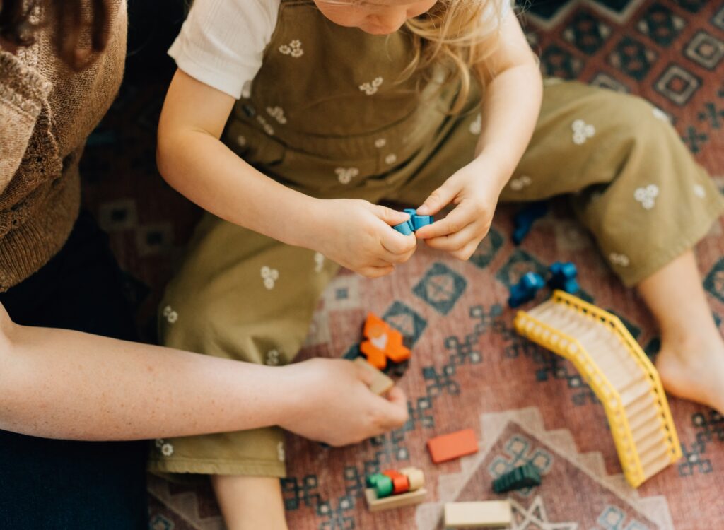 A detail shot of toddler hands holding a small wooden toy piece.
